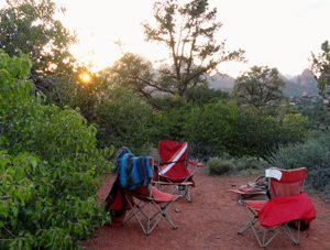 3 chairs in a circle of green trees outdoors in Sedona represents doing Sedona outdoor programs in nature with Crossing Worlds Journeys & Retreats