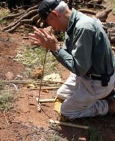 Historical way to make fire by spinning a stick in a notched branch to ignite sparks for fire making.