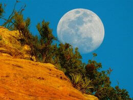 Full moon rising over red cliffs inspires connection with the moon and joyful circle of celestial connection