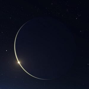 Sliver of light of the crescent new moon in a black sky