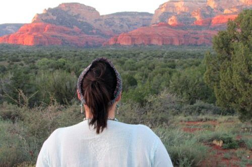 Woman facing the Sedona red cliffs at sunset. This is an earth-spirit circle to tune into the earth at a seasonal turning point, and sense sunset energies. 