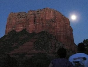 People watching moon coming up behind red cliff at a full moon mystic vision and ceremony circle
