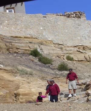 Hopi ancestor cliff trail below a village with 2 men walking with Hopi woman guide and child. 