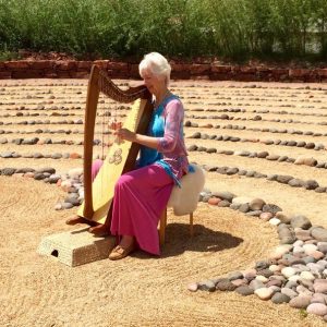 Large labyrinth with woman play harp in center means personalized Sedona ceremonies with harp music can be created to honor, bless, begin something new.