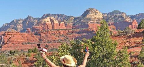 A woman with ceremonial items in uplifted hands as she faces red cliffs symbolizes our Sedona Fall Equinox Celebration, Ceremony and Mystic Vision program